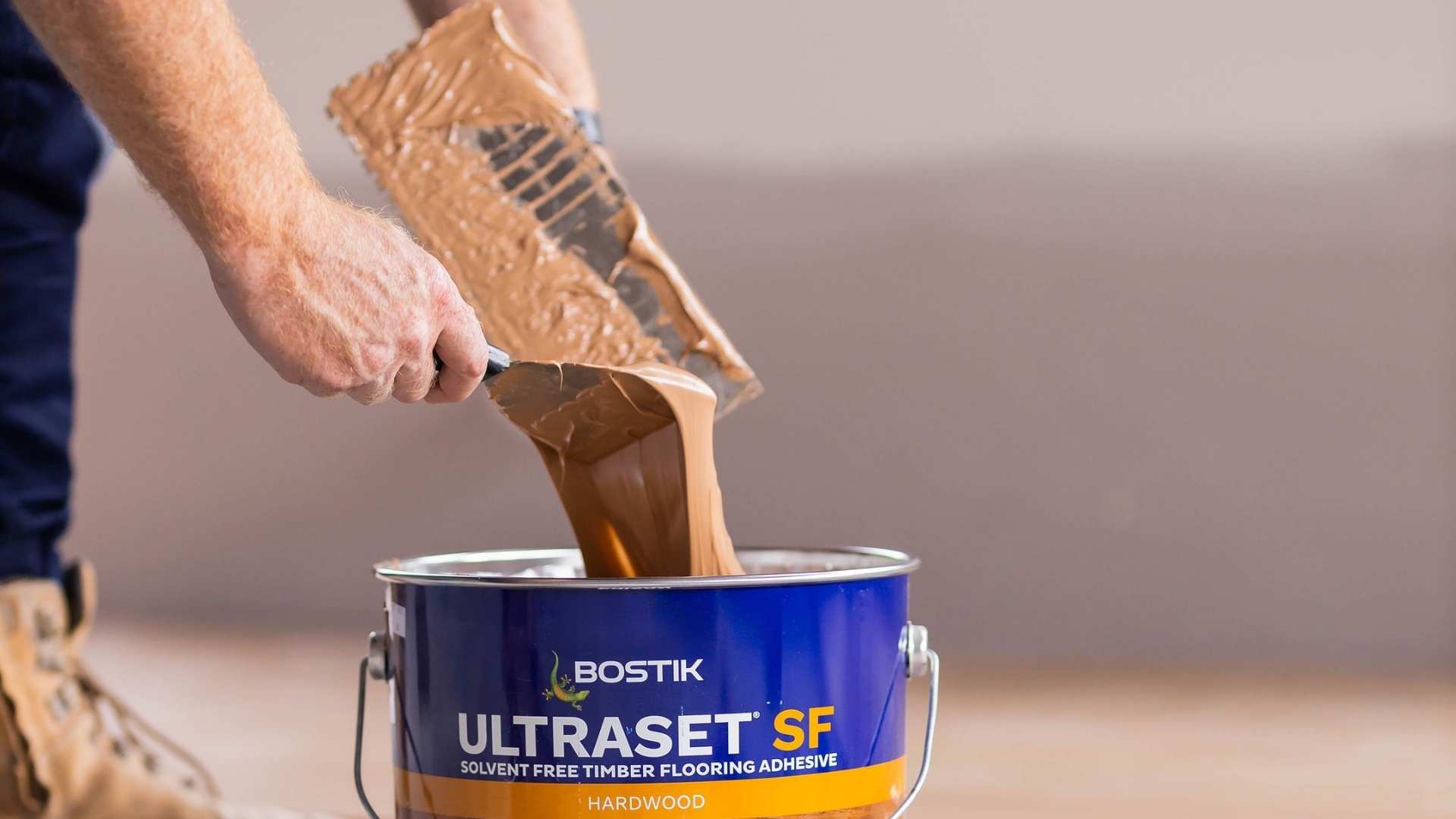 Trade getting Bostik adhesive from tub prior to timber flooring application on concrete.