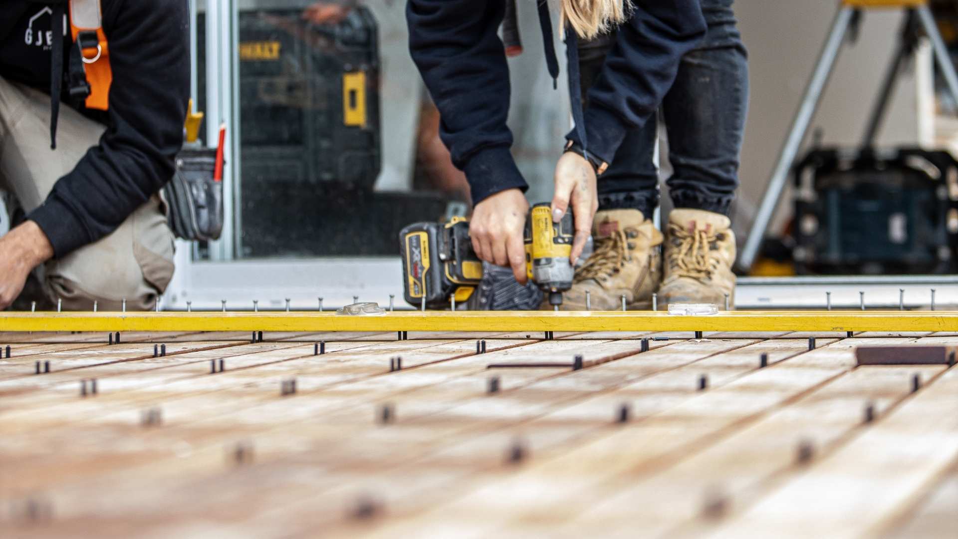 Trades during decking installation ensuring they have proper spacing between each board.