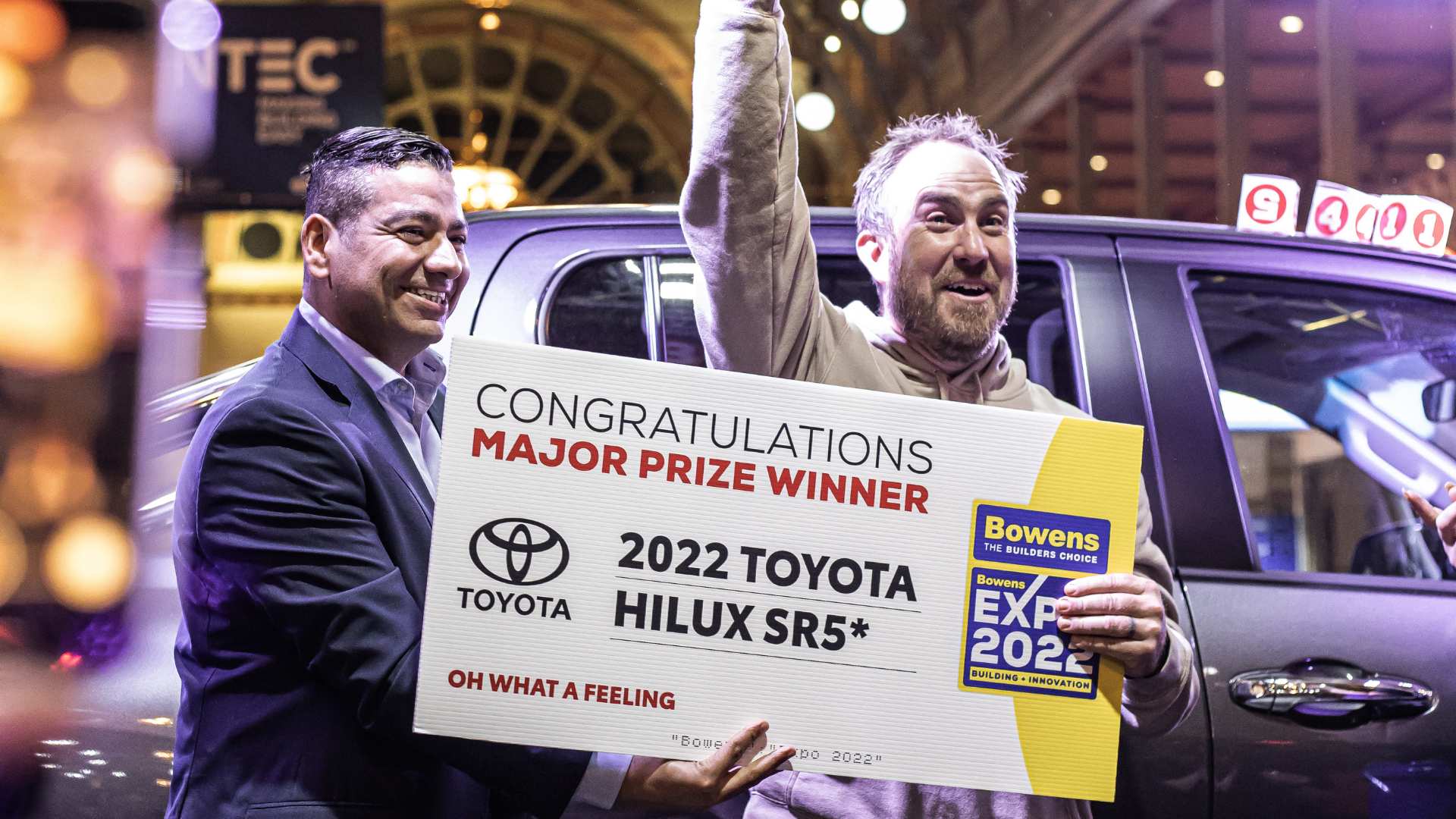 Man celebrates on stage after just winning the free Toyota Hilux.