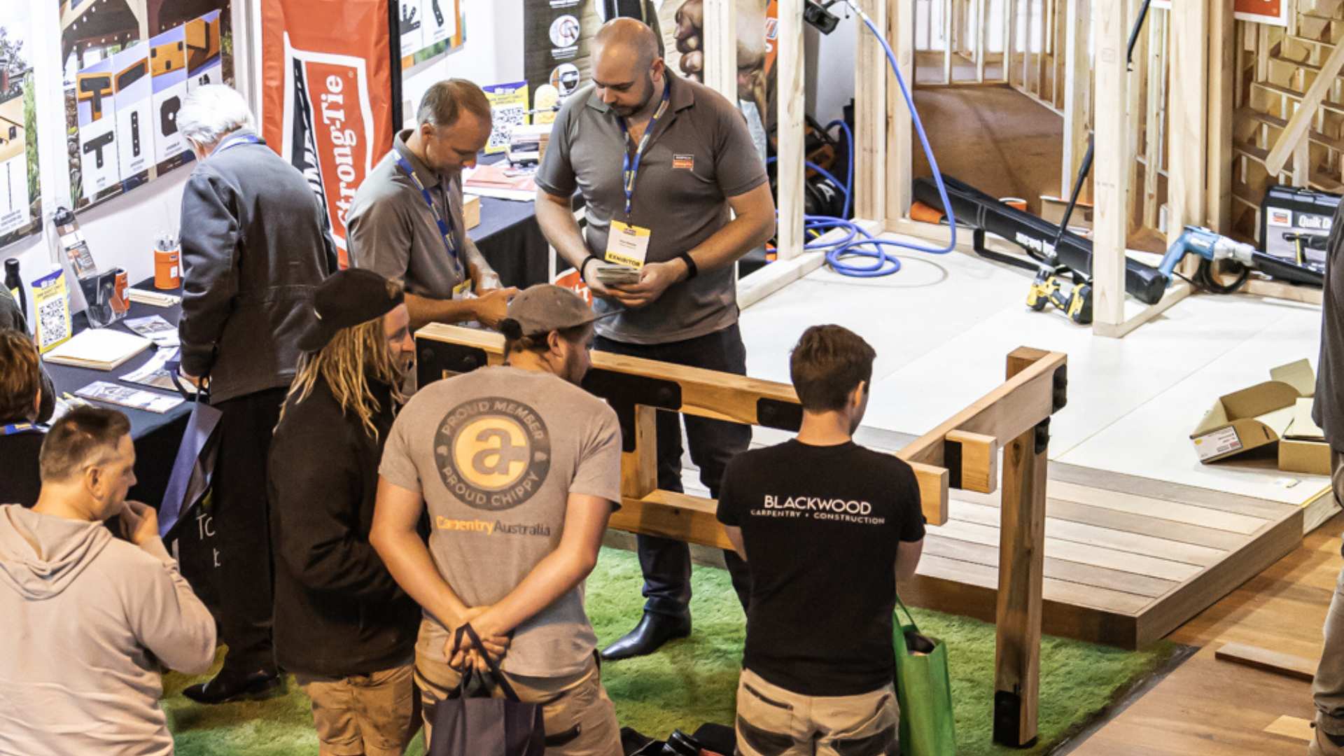 Exhibitors showing products to trades who are watching intently.