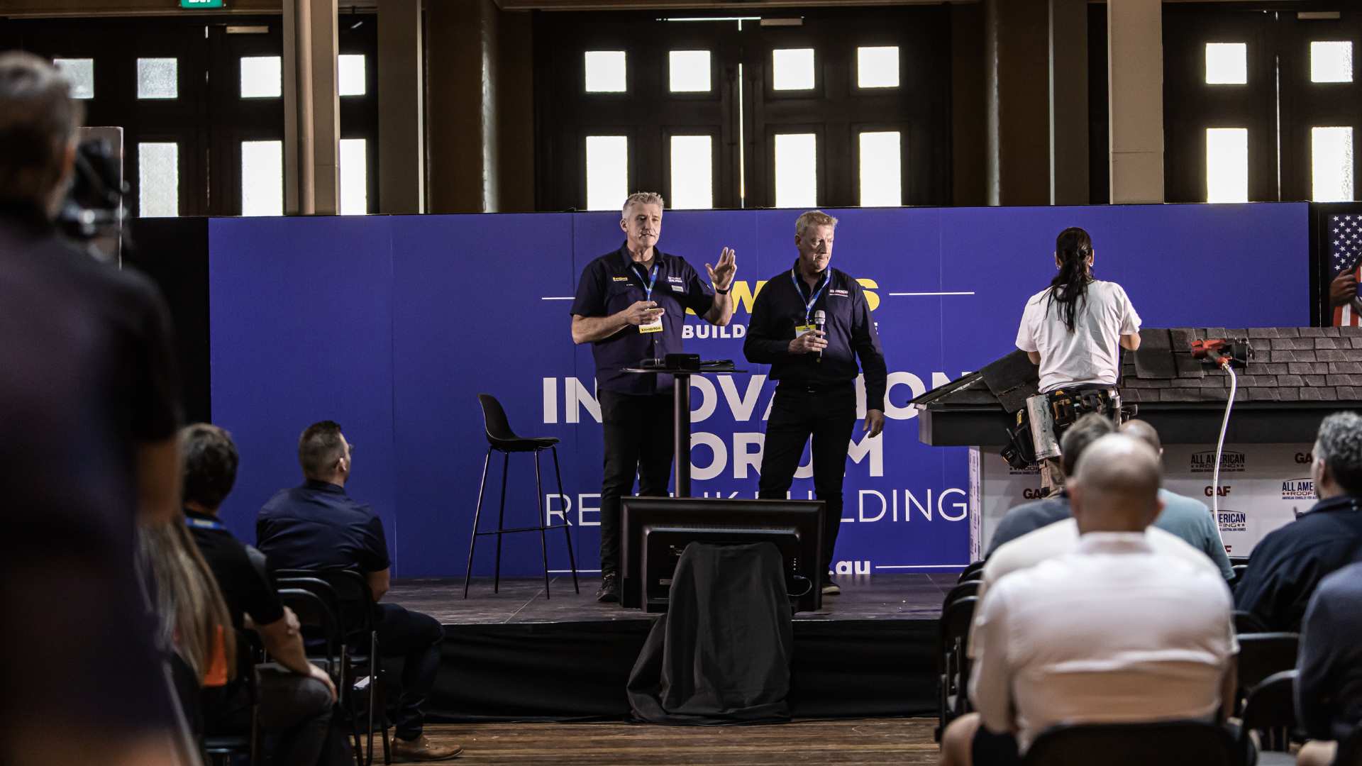 Men presenting on stage in front of trades at the innovation seminar.