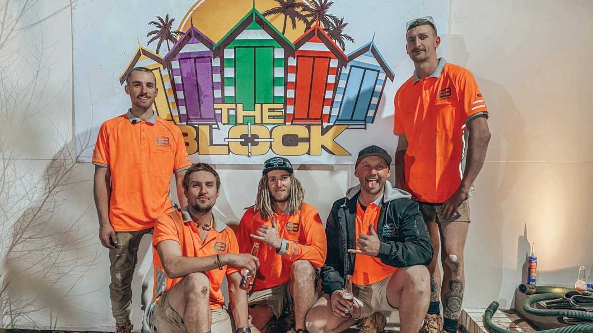 Tradies posing in front of 'The Block' artwork at job site. 
