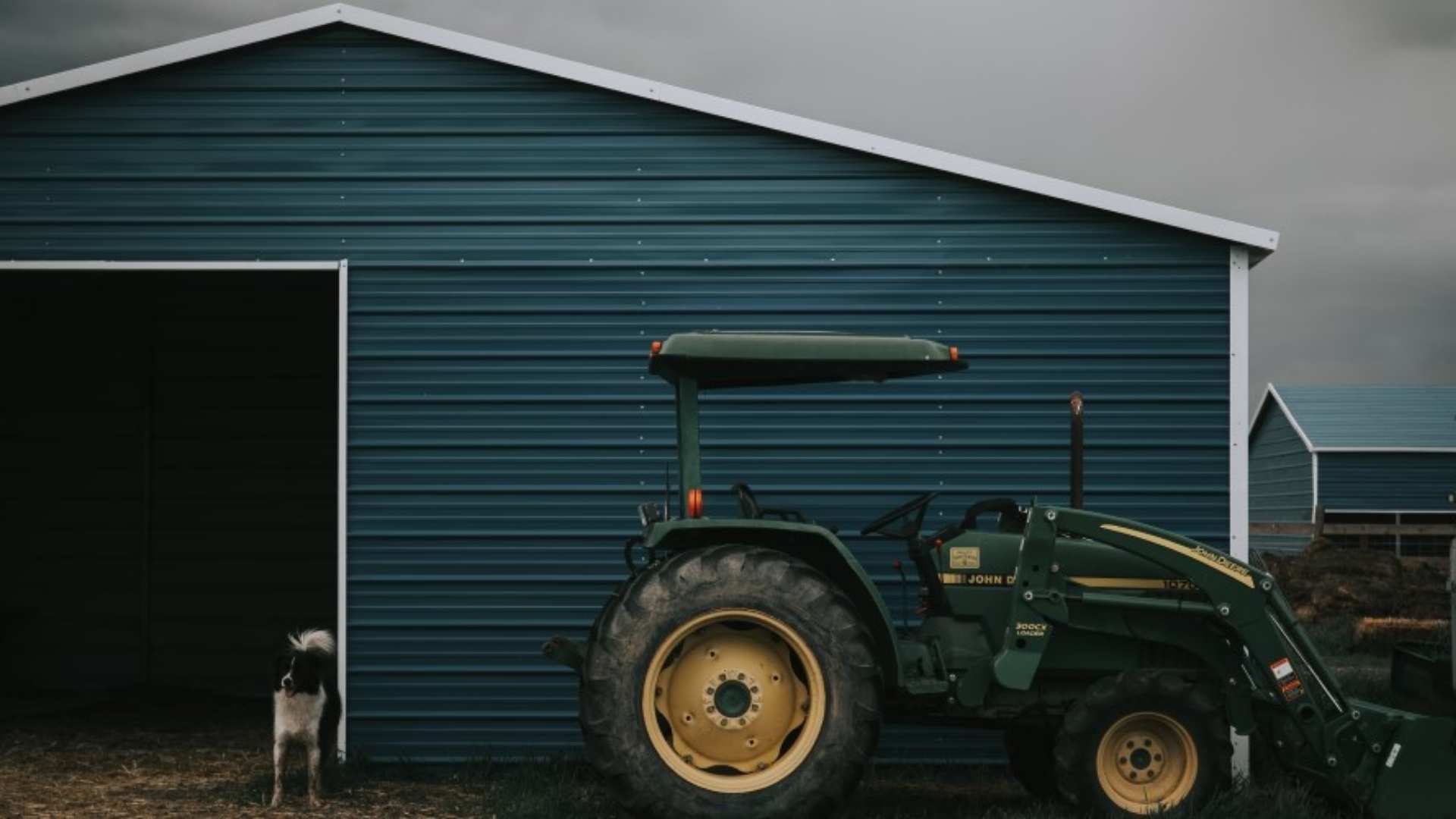 Garden shed on farm with tractor parked in front.
