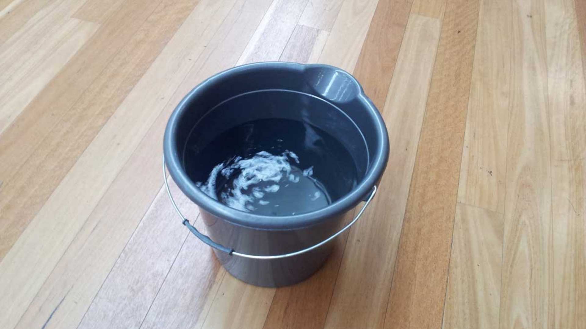 Bucket of water set upon timber flooring.