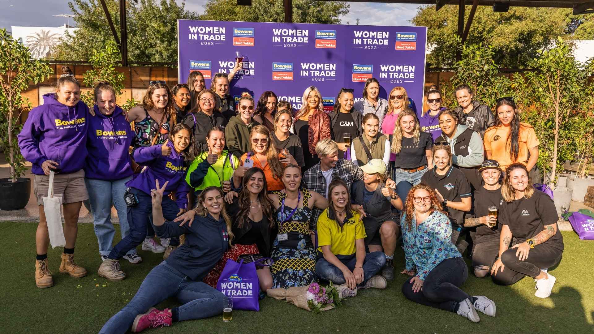 Group of female tradies posing in front of media wall at Bowens Women in Trade 2023.