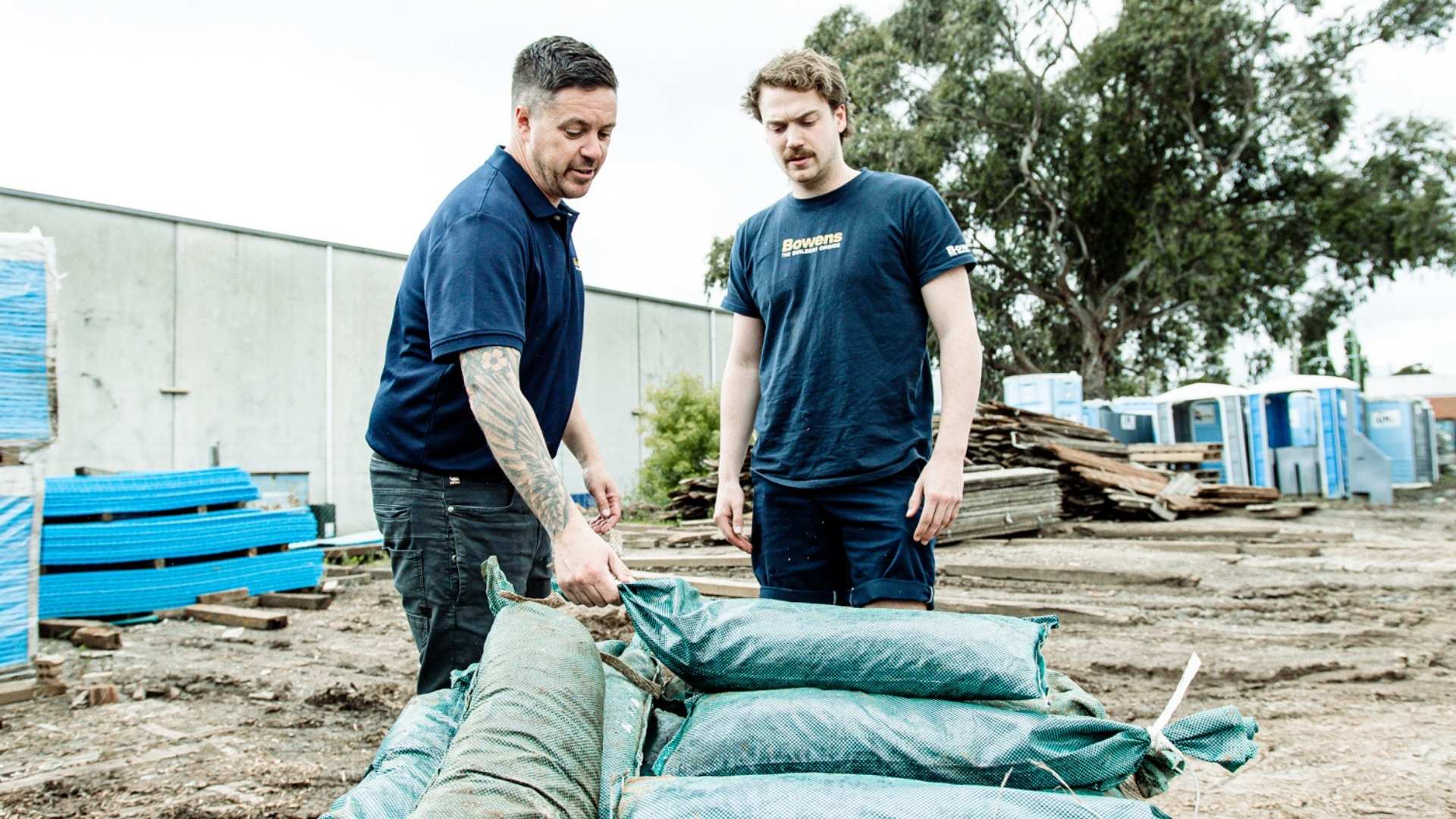Two trades inspecting sandbags at job sites.