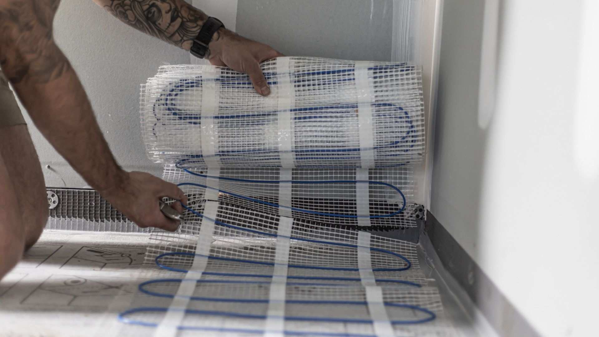 A builder rolling an underfloor heating mat.