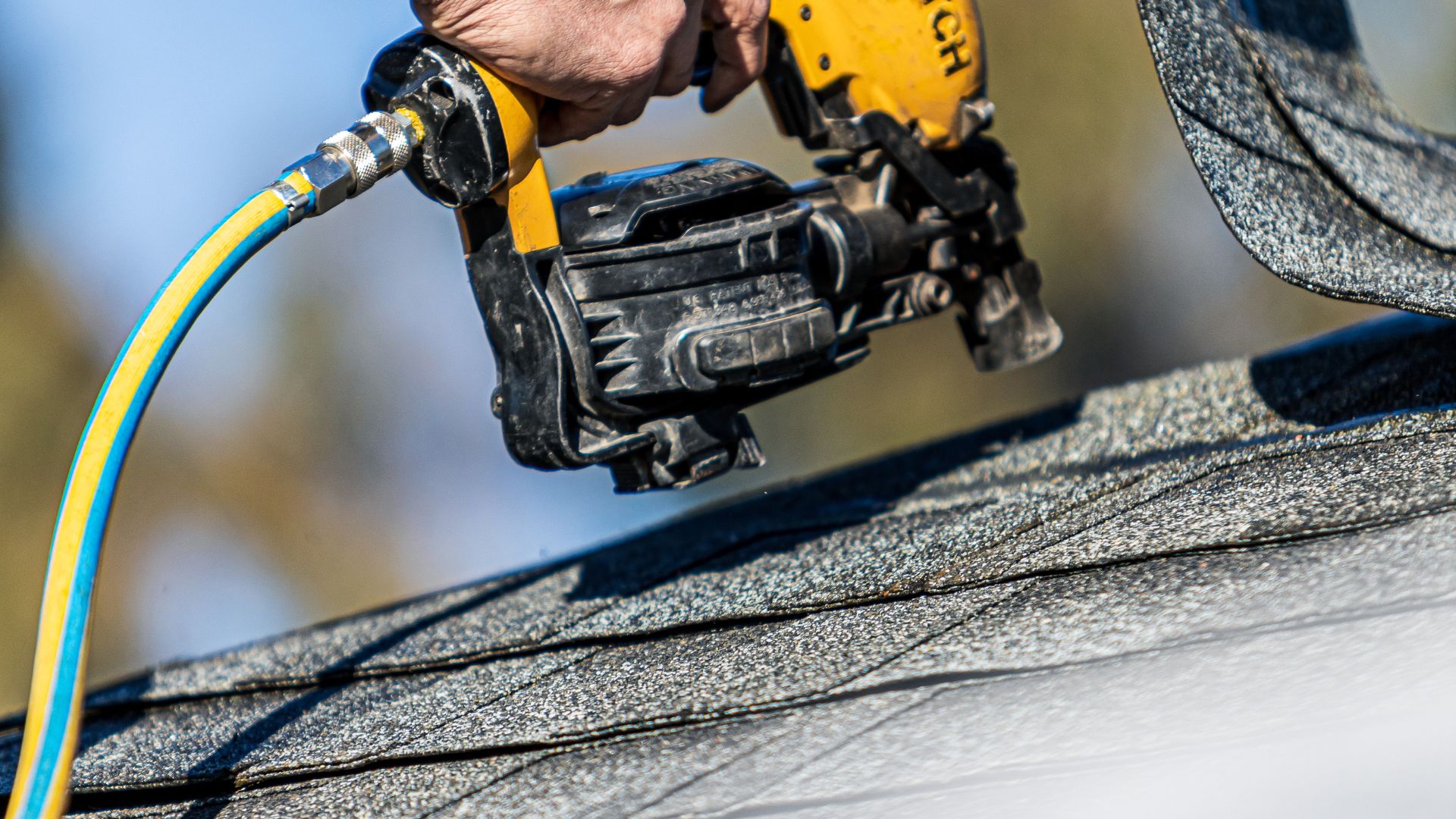 A man using a nailer to install GAF roofing.
