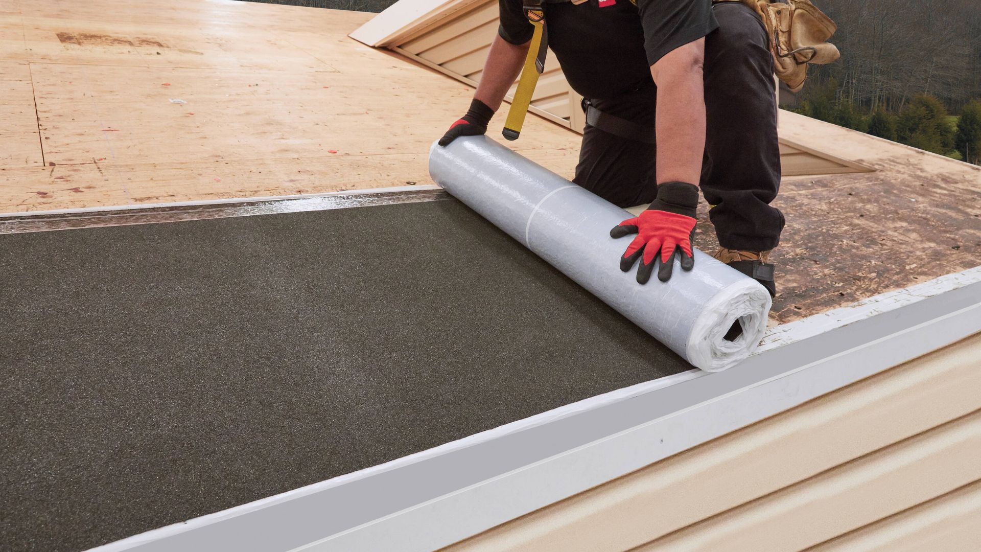 A man installing GAF WeatherWatch® Mineral Surfaced Leak Barrier roofing membrane on a house.