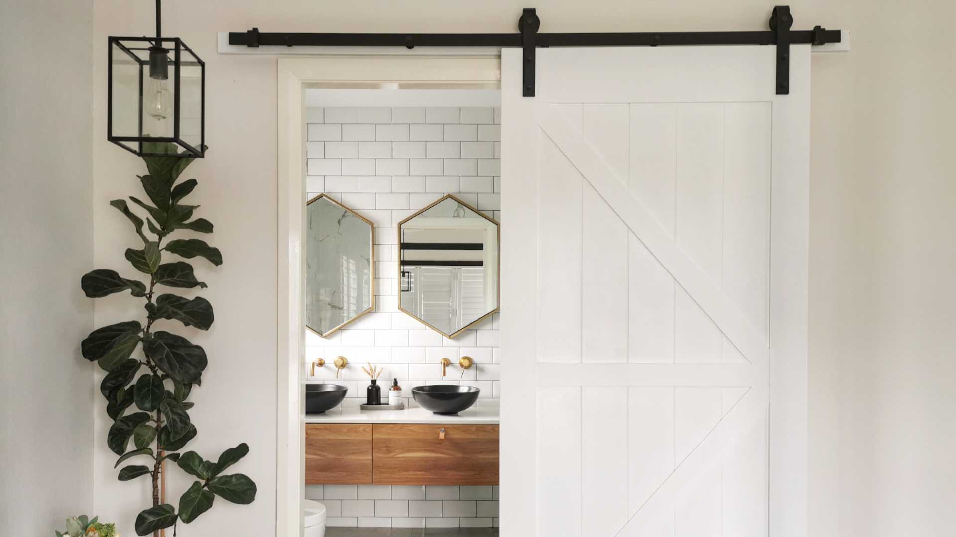 A bathroom with a white barn door and wooden floor.