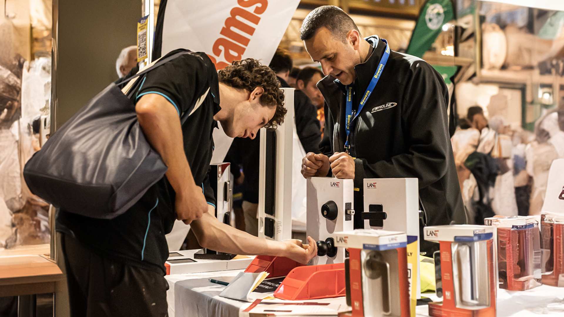 Young trade at exhibitor stand learning about innovative product.