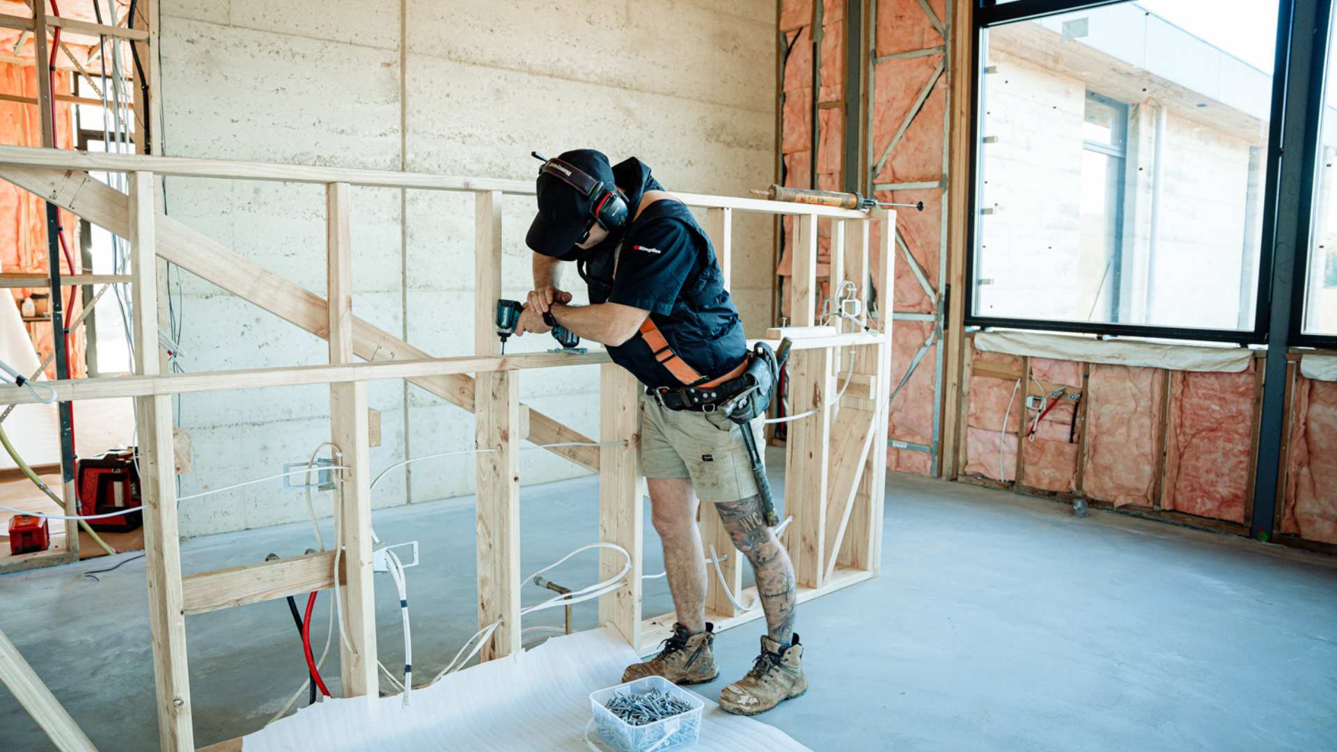 Trade drilling into pine timber frame on job site.