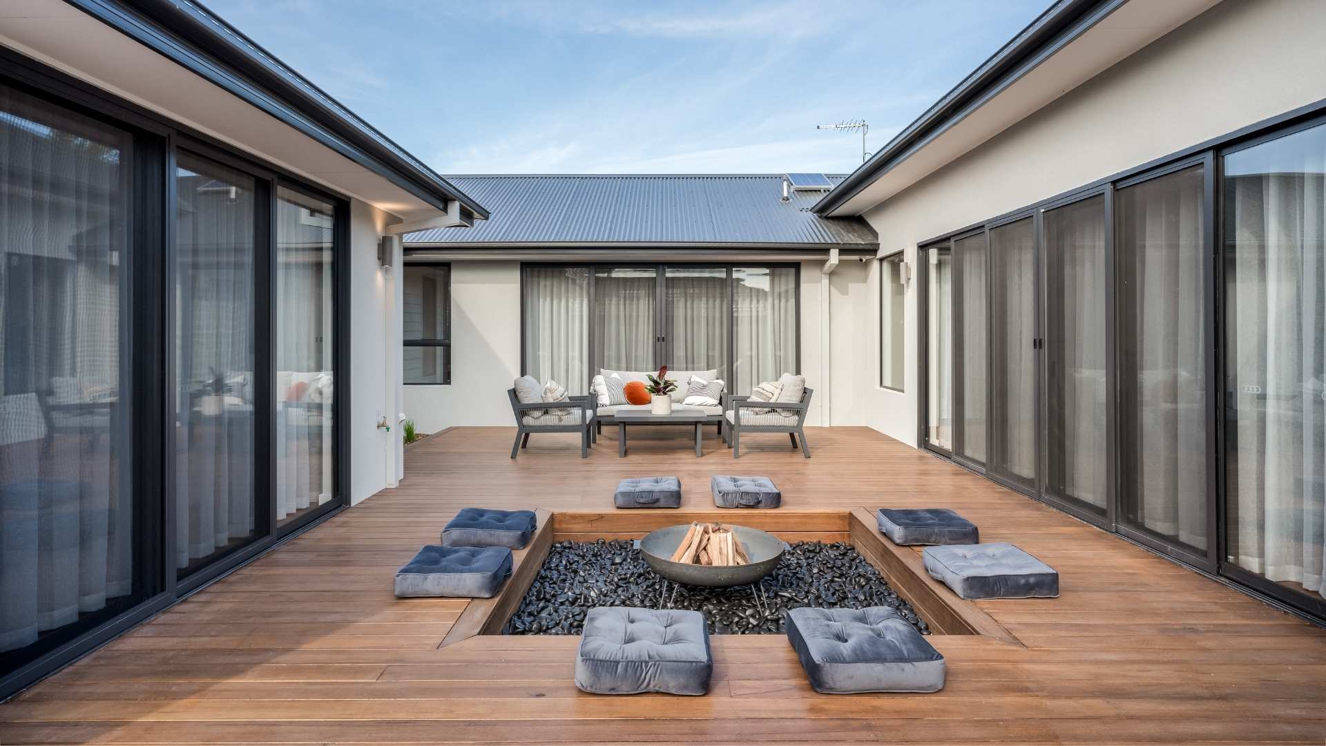 Spotted gum decking with fire pit and surrounding housing.