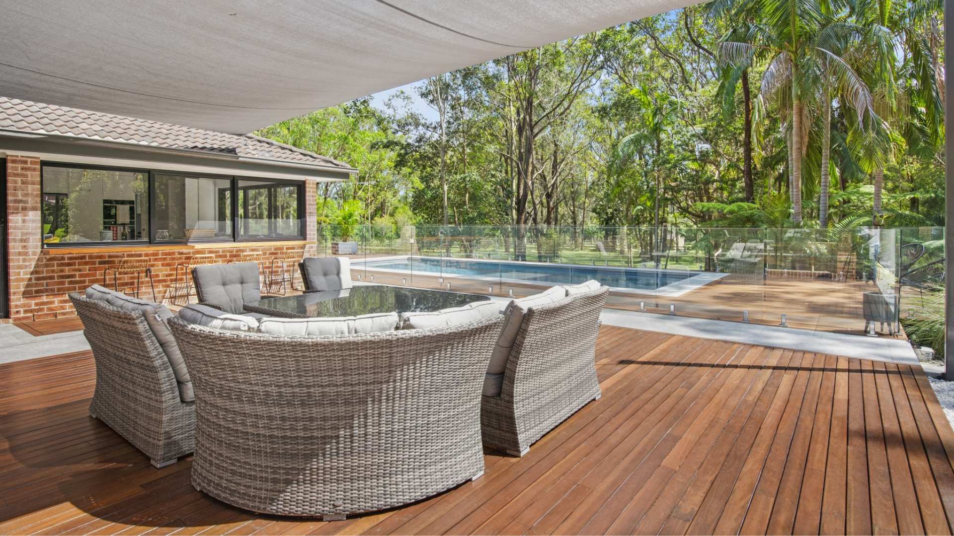 Spotted gum decking used in backyard setting with pool and pool chairs.