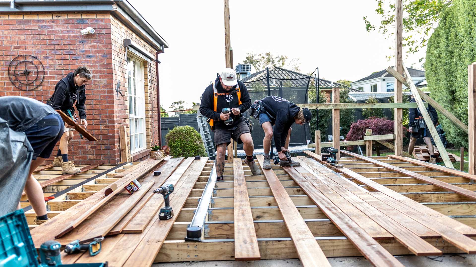 Carpenter installing timber decking on residential job site.