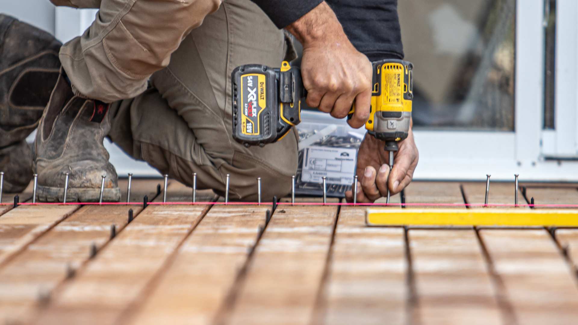 Carpenter drilling in screws for timber decking project with correct spacing.