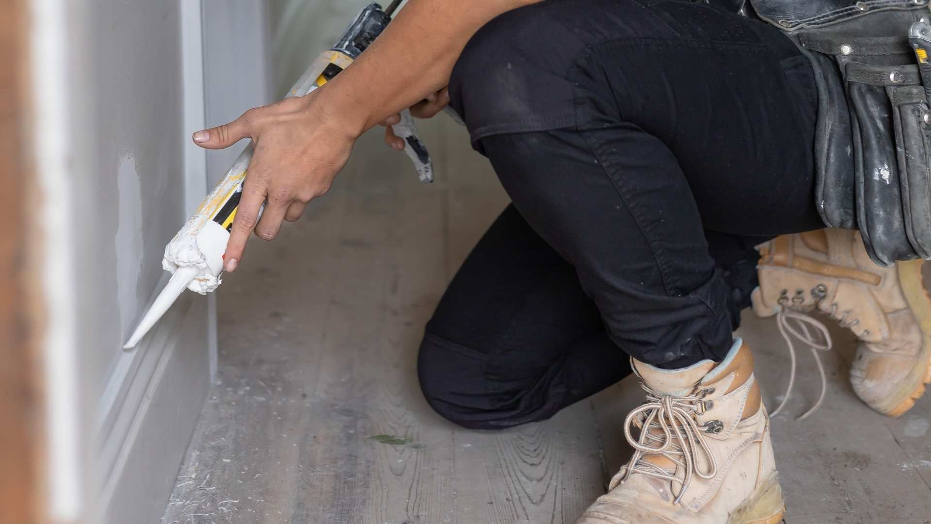 Trade person applying skirting board at home jobsite.