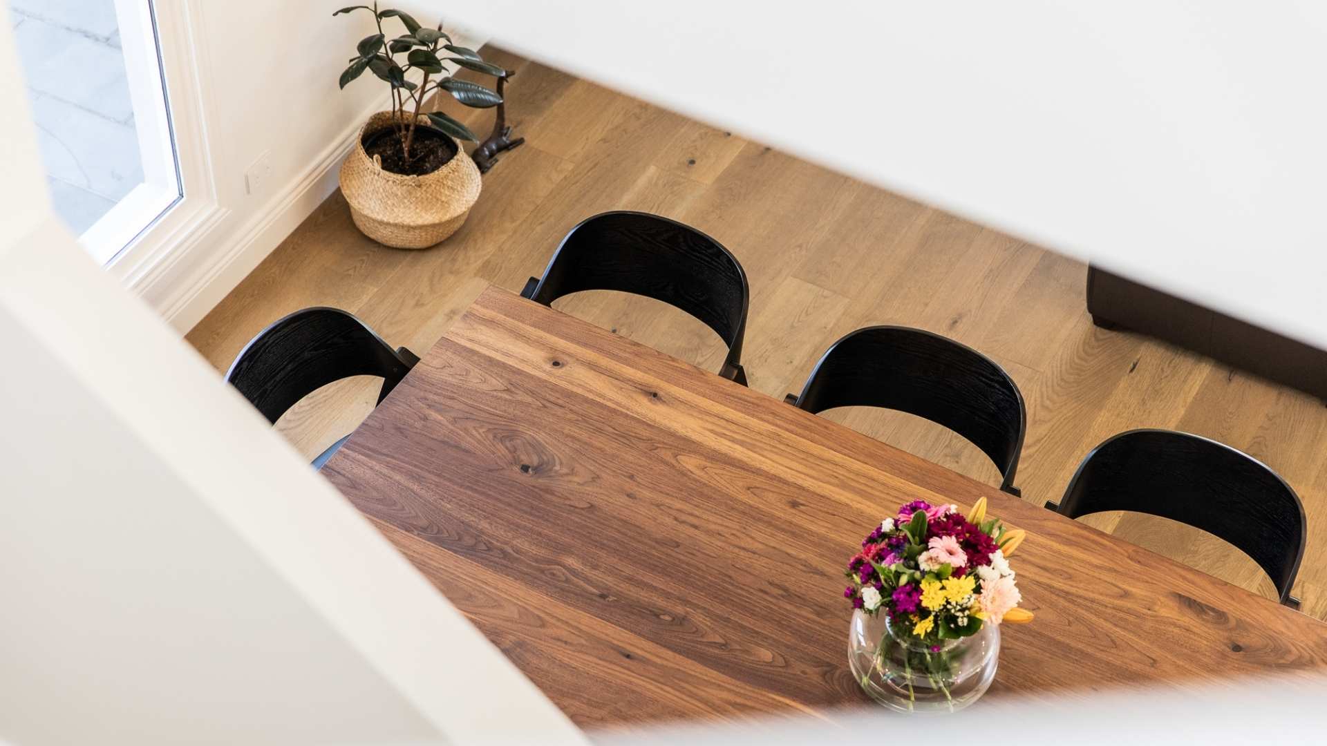 Engineered flooring with dining table and chairs and pot plant in the corner.