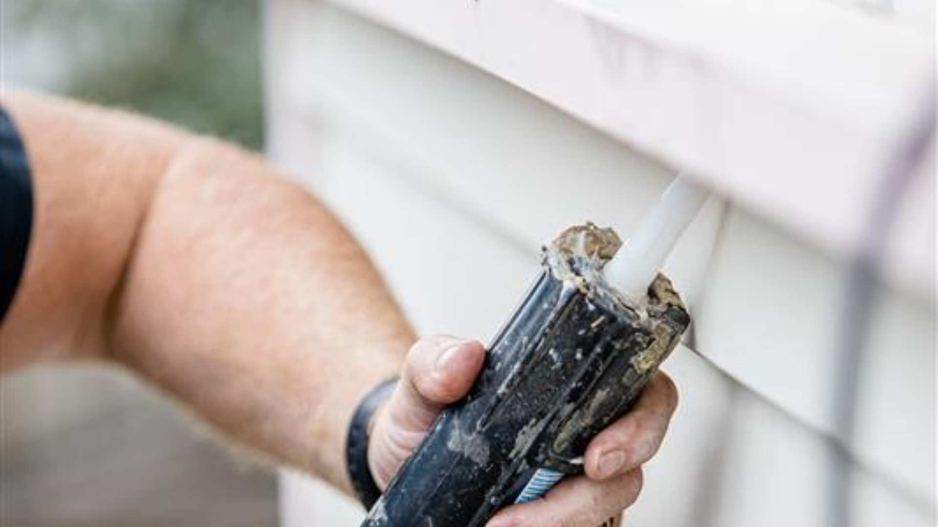 Trade applying sealant under window sill on site.
