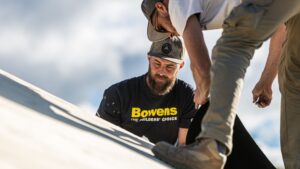 Two trades installing GAF roofing on jobsite.